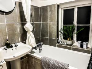 a bathroom with a sink and a bath tub next to a window at Spacious House with 4 parking spaces in Canterbury