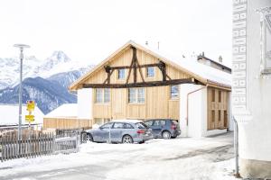 two cars parked in front of a building in the snow at Chasa Muntanella in Ftan