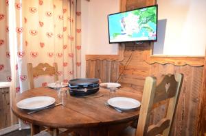 Zimmer mit einem Holztisch und einem TV an der Wand in der Unterkunft Résidence Necou - Studio pour 3 Personnes 954 in Les Menuires
