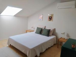 sypialnia z dużym białym łóżkiem z zielonymi poduszkami w obiekcie Chambre d'hotes du grand st-Marc proche Via Rhona w mieście Sorgues