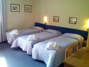 Habitación de hotel con 3 camas y toallas. en Hotel Leon D'Oro, en Pieve di Soligo