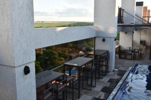 a balcony with tables and chairs and a swimming pool at Alojamiento frente al aeropuerto in Asunción