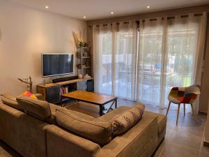 uma sala de estar com um sofá e uma televisão de ecrã plano em Maison proche des Dentelles, et du Mont-Ventoux em Aubignan