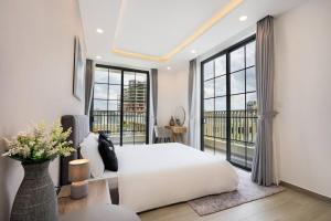 1 dormitorio con cama blanca y ventanas grandes en Wonderland Villa at Ho Tram Beach en Ho Tram