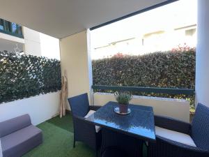 a table and chairs on a balcony with a hedge at Studio Bayonne avec Piscine in Bayonne