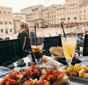 einen Tisch mit einem Teller Essen und zwei Getränken in der Unterkunft TuscanyChalets - luxe family chalet near sea with pool in Viareggio