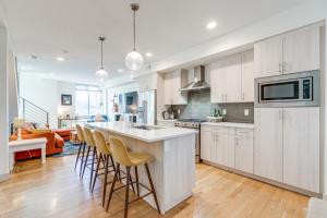 una cocina con armarios blancos y un bar con taburetes en Modern Townhome with Rooftop Deck - Near City Park!, en Denver