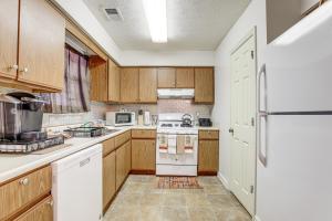 a kitchen with wooden cabinets and a white refrigerator at Georgia Townhome - 3 Mi to Stone Mountain Park! in Stone Mountain