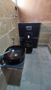 a bathroom with a black toilet in a stall at Earthy - Vintage in Shimoga
