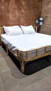 a wooden bed with white sheets and pillows at Earthy - Vintage in Shimoga