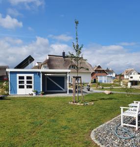 a blue and white house with a tree in the yard at Ferienhaus Utkiek in Poseritz