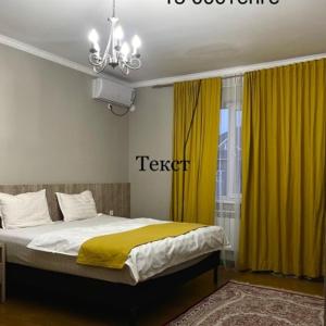 a bedroom with a bed with yellow curtains at MINI HOTEL COMFORT in Shymkent
