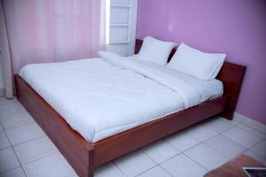 a bed with white sheets and pillows in a room at Nina's Apartment in Kigali