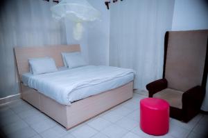 a small bedroom with a bed and a chair at Nina's Apartment in Kigali