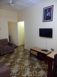 a living room with a couch and a flat screen tv at Lord's Hands Guesthouse Hotel in Winneba