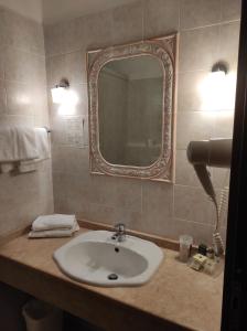 Hotel Le Mura في فولينيو: حمام مع حوض ومرآة