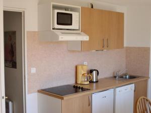 a kitchen with a microwave and a stove top oven at Résidence Royal Peyragudes Mp - Studio pour 4 Personnes 994 in Germ