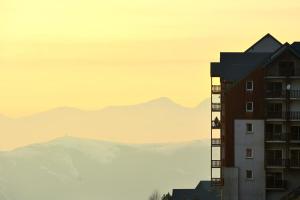 a tall building with mountains in the background at Résidence Royal Peyragudes Mp - Studio pour 4 Personnes 994 in Germ