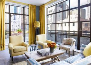 纽约惠特比酒店的客厅配有椅子、桌子和大窗户
