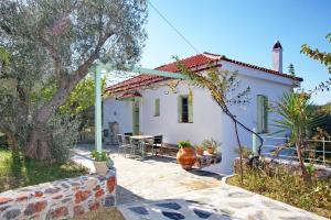 a white house with a table and a tree at Cherry Cottage in Alikias