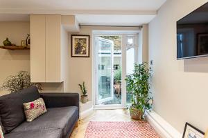 a living room with a couch and a sliding glass door at Cosy Garden Flat in Prestigious Residential Area in London