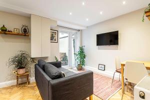 a living room with a couch and a tv at Cosy Garden Flat in Prestigious Residential Area in London