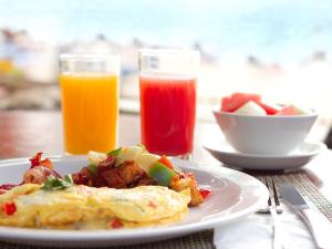 a plate of breakfast food with eggs and a bowl of fruit at Coconut Court Beach Hotel in Bridgetown
