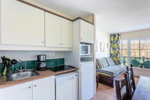 a kitchen with white cabinets and a living room with a couch at Résidence Les Belles Rives - maeva Home - Appartement 2 pièces 7 personnes 084 in Argentat