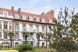 a large brick building with trees in front of it at Résidence Presqu'Ile de la Touques - Appartement 3 pièces 6 personnes - Ex 334 in Deauville