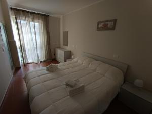 a large white bed in a bedroom with a window at La Casetta per te in Gravina di Catania