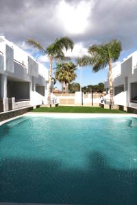 a swimming pool in front of a building with palm trees at Elvira Home San Gines AQ-104 in Santiago de la Ribera