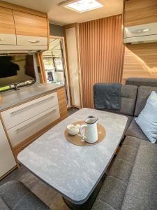einen Tisch in einem Wohnwagen mit einer Kaffeetasse drauf in der Unterkunft George Glamper MEERZEIT in Belau