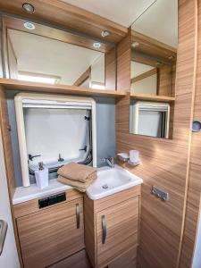 ein Bad mit einem Waschbecken und einem Spiegel in der Unterkunft George Glamper MEERZEIT in Belau