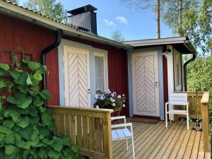 a red house with a deck with two chairs at Himalayan cabin Inkoo in Inkoo