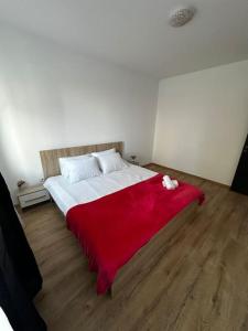 um quarto com um cobertor vermelho numa cama em Cozy 2 bed flat em Sînpetru