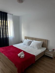 uma cama com um cobertor vermelho e duas toalhas em Cozy 2 bed flat em Sînpetru