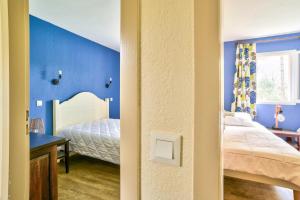 1 dormitorio con paredes azules, 1 cama y escritorio en Les maisons du Domaine du Golf de Pinsolle - maeva Home - Maison 3 pièces 6 324, en Soustons