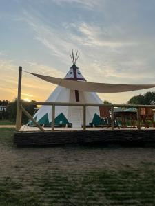 a large white tent with chairs in a field at Tipi Sioux in Belau