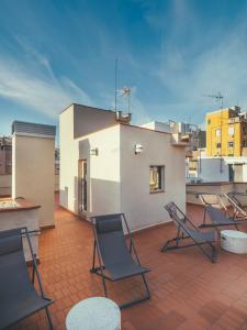 eine Terrasse mit Stühlen und Tischen auf dem Dach in der Unterkunft Boutique Apartments 23 Barcelona in Barcelona