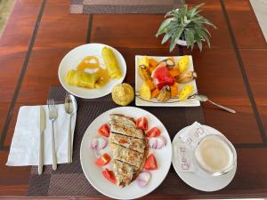 une table avec trois assiettes de nourriture et une tasse de café dans l'établissement Hari Villa Mirissa, à Mirissa