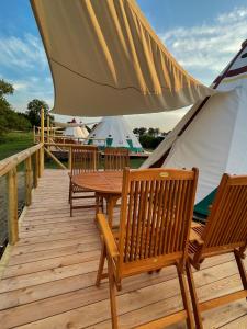a wooden deck with chairs and a table and tents at Tipi Apachen in Belau