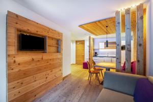 uma sala de estar com uma parede de madeira e uma televisão em Stoana Apt 2-5 em San Giacomo