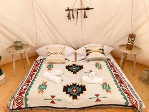 a bed in a tent with towels and pillows at Tipi Kiowa in Belau