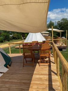 a wooden deck with a table and chairs under a tent at Tipi Blackfoot in Belau
