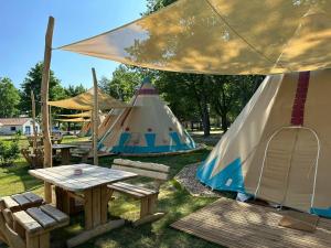 - un groupe de tentes, une table de pique-nique et des bancs dans l'établissement Tipi Missouri, à Falkenberg