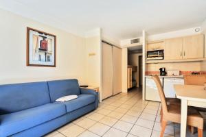 a living room with a blue couch and a kitchen at Résidence Héliotel Marine - maeva Home - Studio 4 personnes - Confort 084 in Cros-de-Cagnes