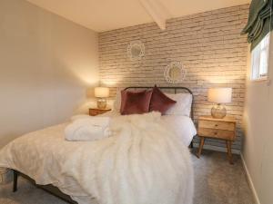 sypialnia z białym łóżkiem z ceglaną ścianą w obiekcie The Lodge at Wildersley Farm w mieście Belper