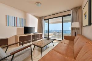 ein Wohnzimmer mit einem Sofa und einem TV in der Unterkunft Olée Nerja Holiday Rentals by Fuerte Group in Torrox Costa