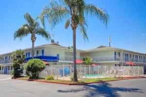 a building with palm trees and chairs in front of it at Motel 6-Tulare, CA in Tulare