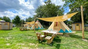 un groupe de tentes dans un champ avec une table et des chaises dans l'établissement Tipi Alabama, à Falkenberg
